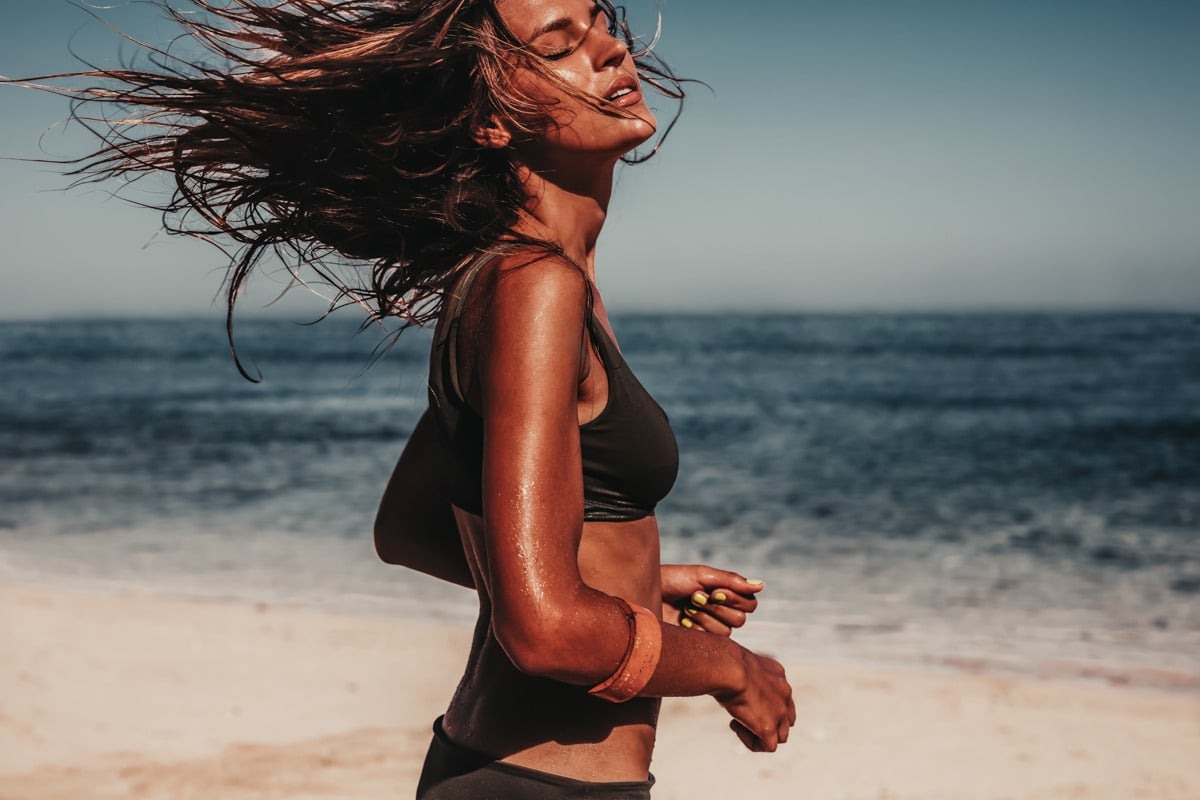 Shot of young woman in bikini running on the beach. Caucasian female model on the sea shore.